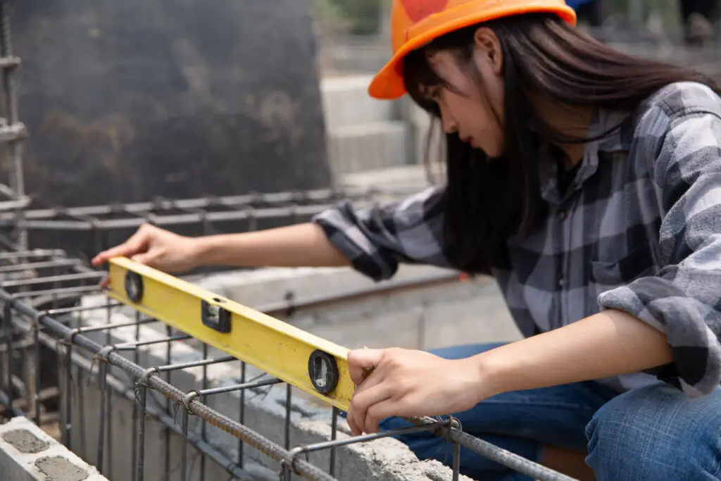 Foundation contractor checking concrete foundation reinforcement with a level on a construction site.