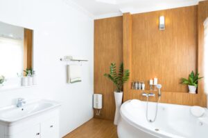 Modern bathroom with a white bathtub, wood-paneled walls, vanity, and indoor plants.